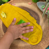 kind rolt een patroon in de gele klei met de klei roller.