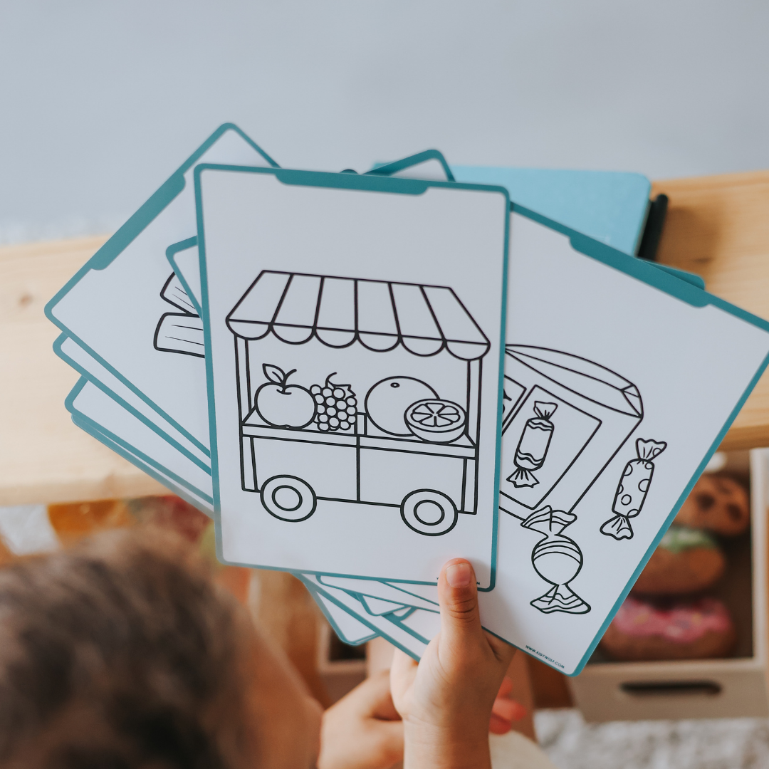 Kind houdt een waaier overtrekkaarten van het marktthema vast