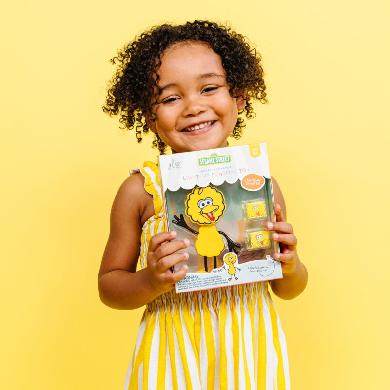 Meisje houdt de verpakking met het Big Bird speelvriendje vast 