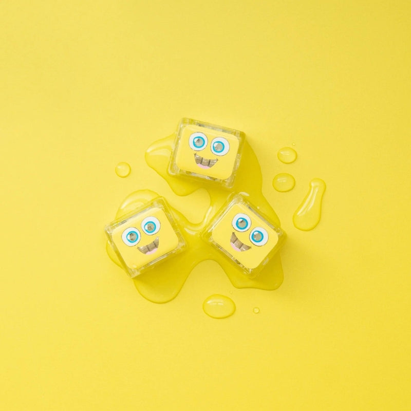 Drie sensorische blokjes van Glo Pals in een plasje water op een gele achtergrond.