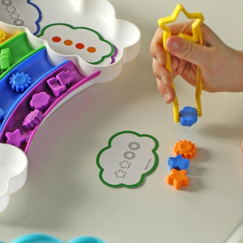 Kind maakt een patroon van de figuurtjes uit de sorteerset met de tang