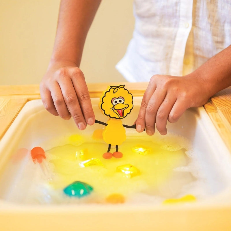 Glo Pals Big Bird speelvriendje wordt boven een badje met water gehouden.