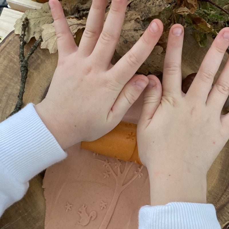 kind rolt met twee handen een patroon in het klei