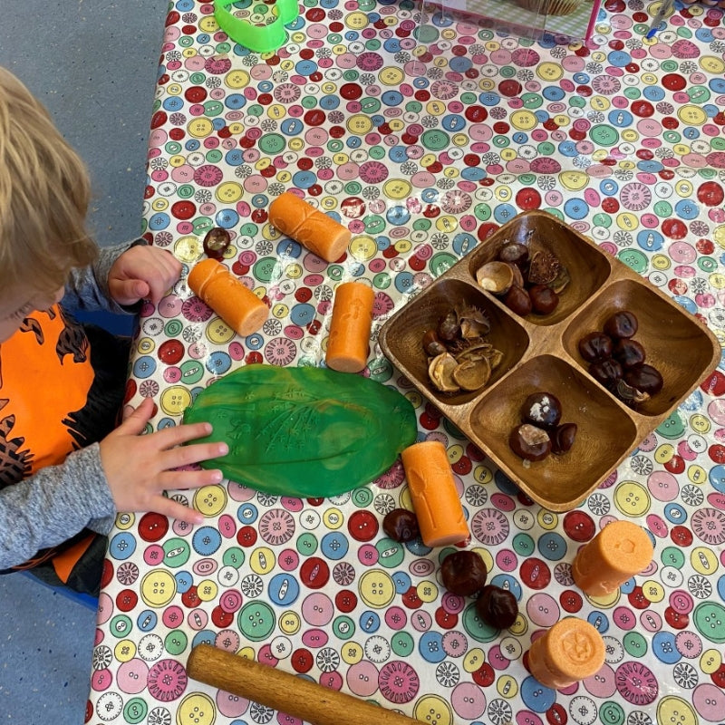 kind speelt met groen klei, de klei rollers en kastanjes 