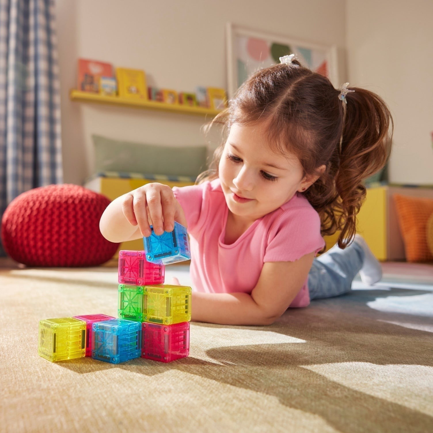 Kinder Wonderland meisje bouwt met kleurrijke magnetische Magna-Tiles Cubes in een gezellige kinderkamer