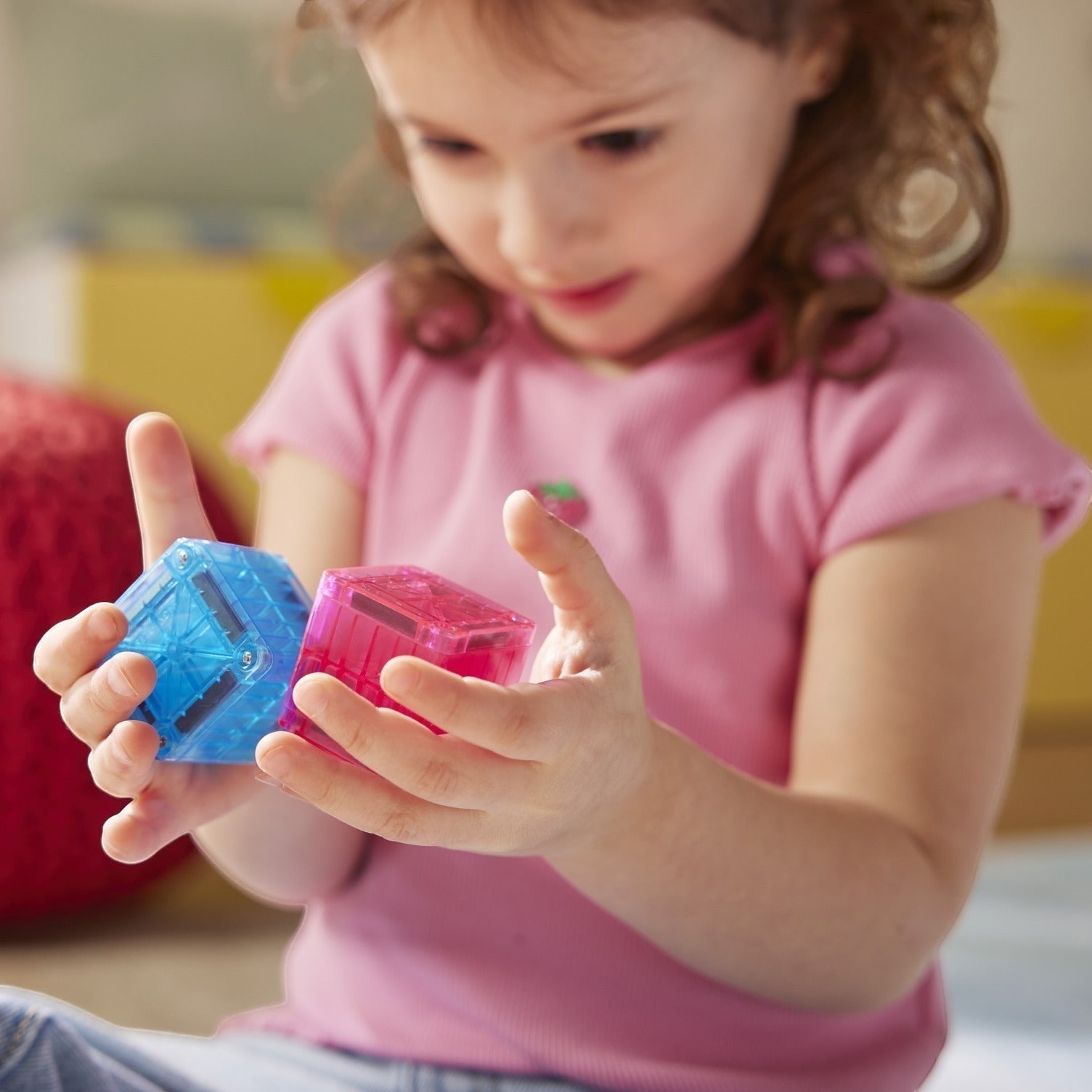 Kinder Wonderland kind speelt met blauwe en roze magnetische Magna-Tiles kubussen voor 3D constructies